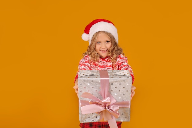 a beautiful blonde girl in a Christmas jumper Santa Claus hat holds a gift box