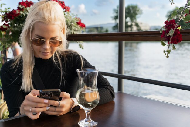 A beautiful blonde girl of European appearance in sunglasses and with a mobile phone in her hands
