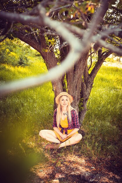 자연에서 모자, 격자 무늬 셔츠와 드레스에 아름 다운 금발 소녀