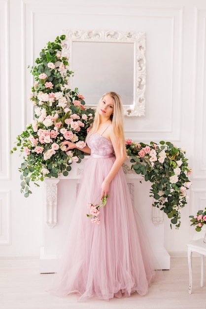 Красивая белокурая девушка в длинном мягком фиолетовом платье представлять цветков. концепция парфюмерии, моды и красоты