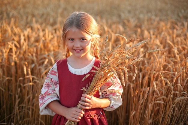 밀밭의 석양에 민족 의상을 입은 아름다운 금발 소녀