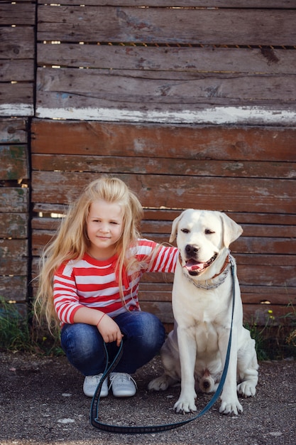 그녀의 강아지와 함께 연주 아름 다운 금발 소녀입니다. 야외 초상화. 시리즈
