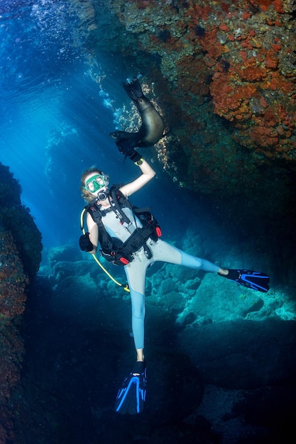 Beautiful blonde girl playing with sea lion underwater