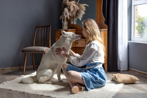 Beautiful blonde girl playing with white husky dog