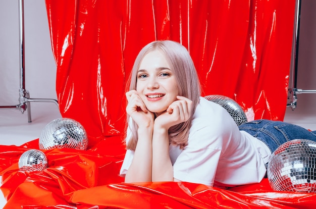 Beautiful blonde girl posing at studio on a red