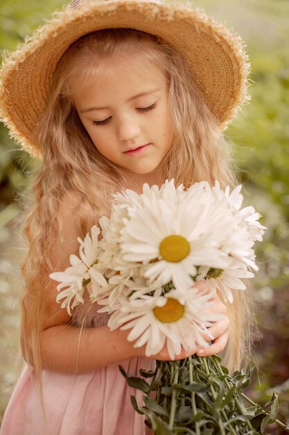 a beautiful blonde girl in a straw hat with white daisies in her hands