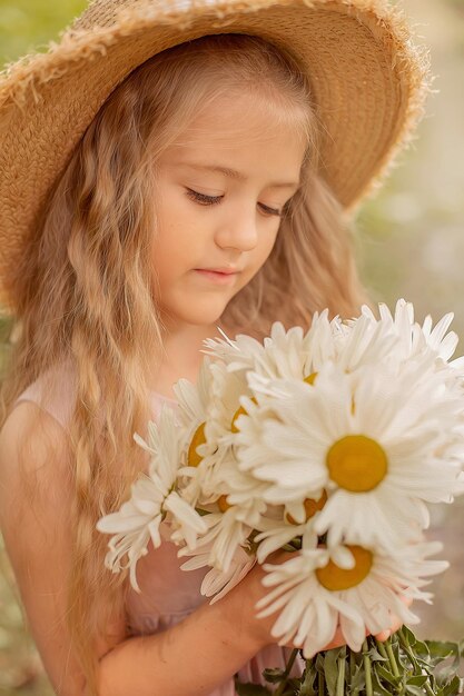 a beautiful blonde girl in a straw hat with white daisies in her hands