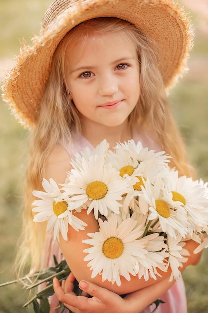 a beautiful blonde girl in a straw hat with white daisies in her hands