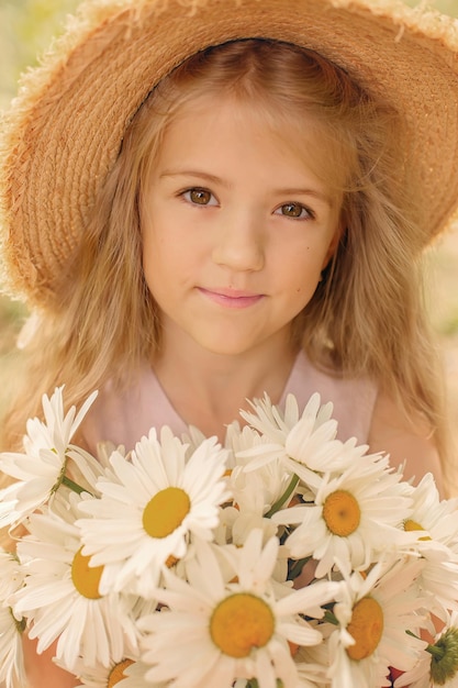 a beautiful blonde girl in a straw hat with white daisies in her hands