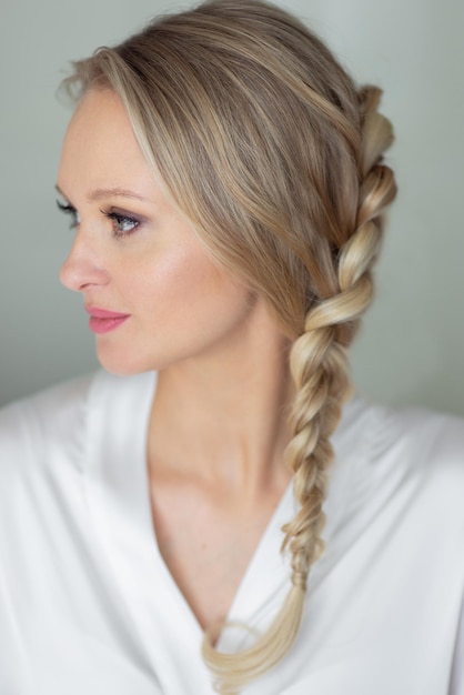 Beautiful blonde girl with braided hair in white dressing gown