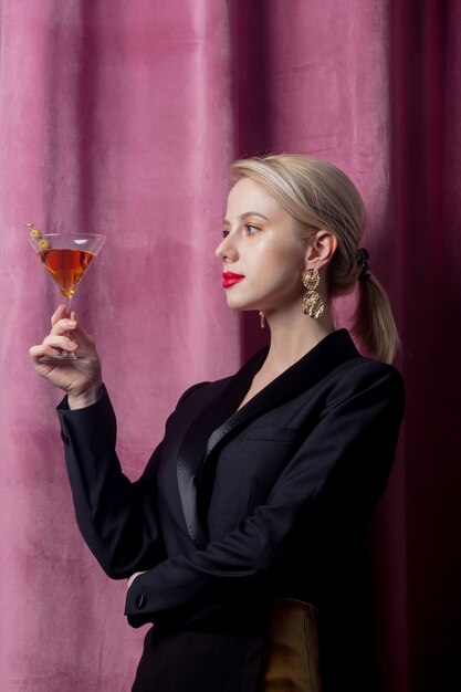 Beautiful blonde girl with cocktail on suede