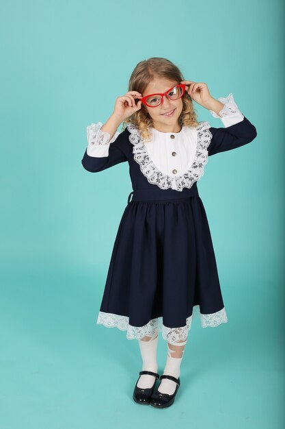 a beautiful blonde girl with curly hair wearing glasses with red frames and a blue school uniform