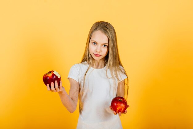 Beautiful blonde girl with red apple in studio