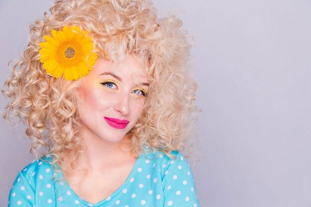 Beautiful blonde girl with voluminous curly hairstyle, in a blue polka dot blouse