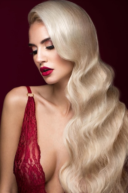 Beautiful blonde in a hollywood manner with curls red lips lingerie beauty face and hair
