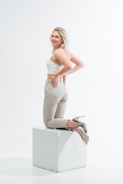 Beautiful blonde in jeans in the studio on a light background