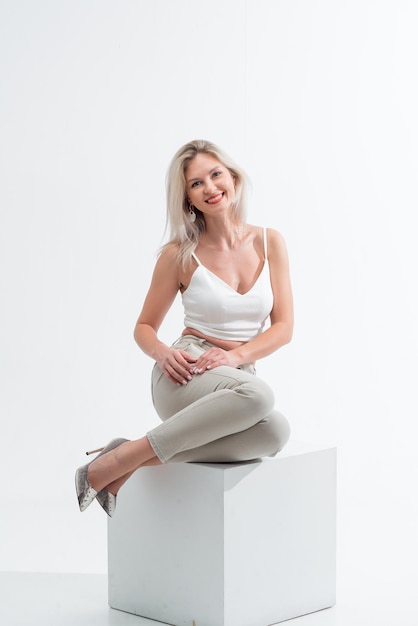 Beautiful blonde in jeans in the studio on a light background