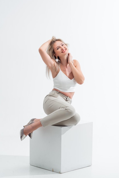 Beautiful blonde in jeans in the studio on a light background