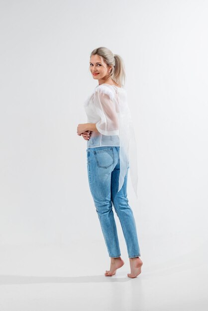 Beautiful blonde in jeans in the studio on a light background