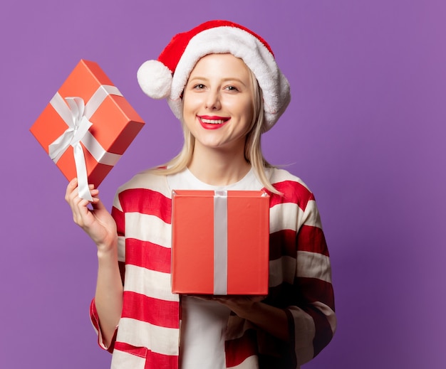 Beautiful blonde in red jacket with gift box on puprle background