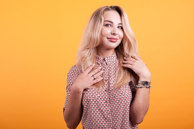 Beautiful blonde in short dress in studio over yellow background