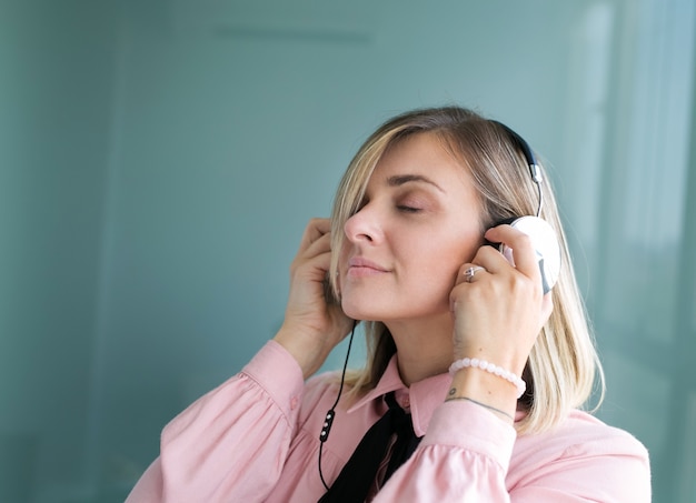 Beautiful blonde in silver headphones listens to music