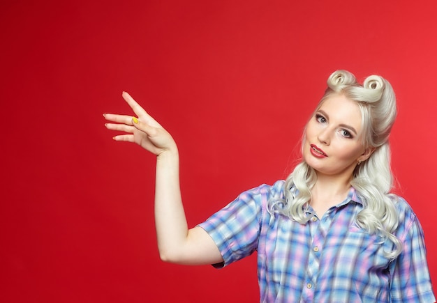 Beautiful blonde with a big candy, posing on a red background