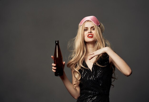 Photo beautiful blonde with a bottle of beer in her hand and a pink mask on her head