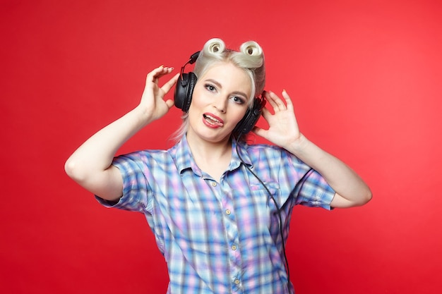 Beautiful blonde with headphones posing on a red background