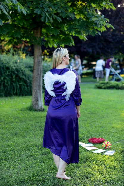 Beautiful blonde with long hair and long purple dress is balancing in public park