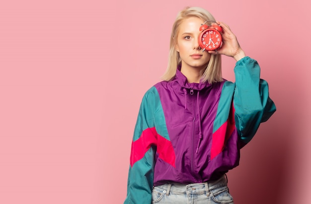 Beautiful blonde woman in 90s clothes with alarm clock