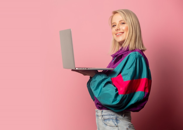 Beautiful blonde woman in 90s clothes with laptop computer