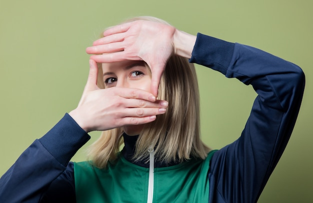 Beautiful blonde woman in 90s sport suit on green background