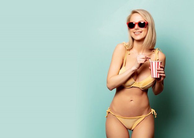 Beautiful blonde woman in bikini with paper cup