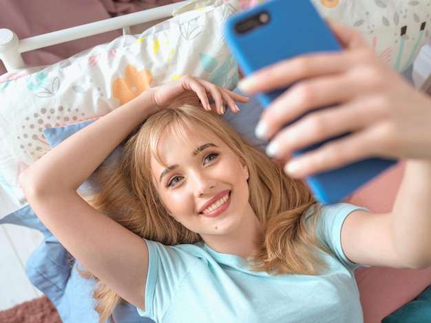 Blogger bella donna bionda che fa selfie con il suo smartphone