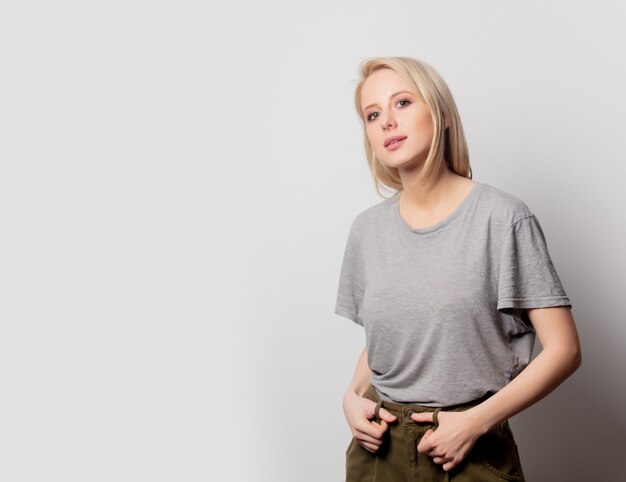 Beautiful blonde woman in brown t-shirt on white wall