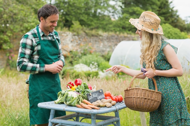 Beautiful blonde woman buying vegetables at farmers market