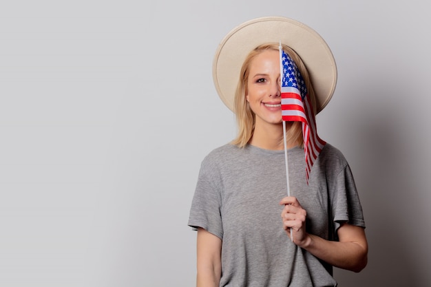 Photo beautiful blonde woman in cowboy hat with usa flag on white wall