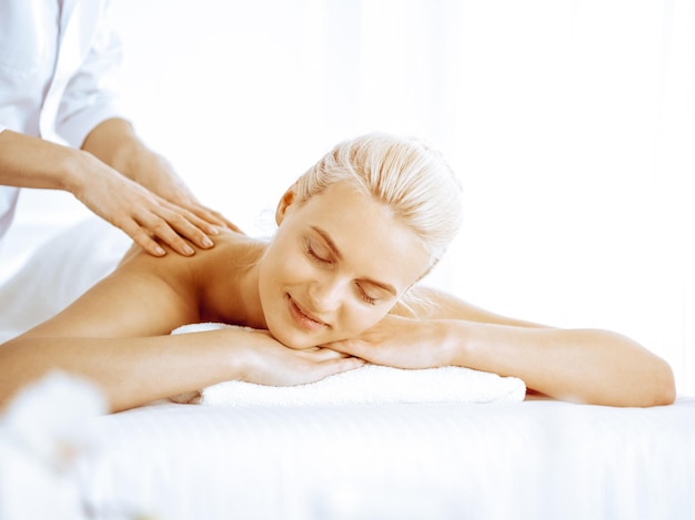 Beautiful blonde woman enjoying back massage in spa center Beauty and lifestyle