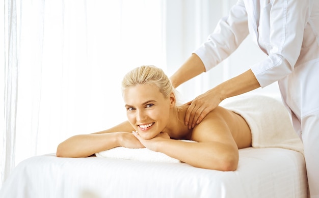 Photo beautiful blonde woman enjoying back massage with closed eyes. spa salon concept.