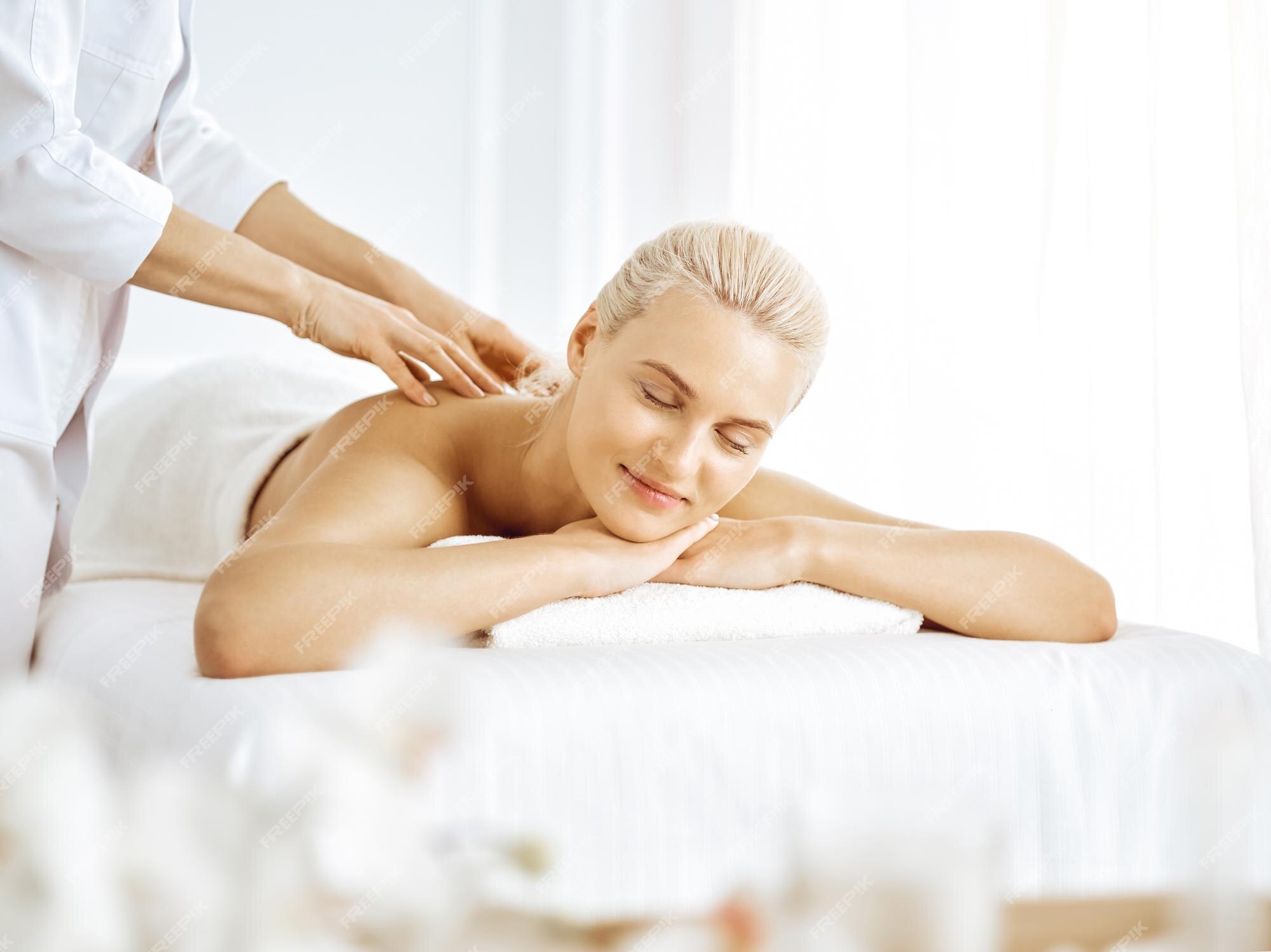 happy blonde girl with a towel on her head enjoying a back massage in the  spa senter. close up photo. happiness,health, body care Stock Photo