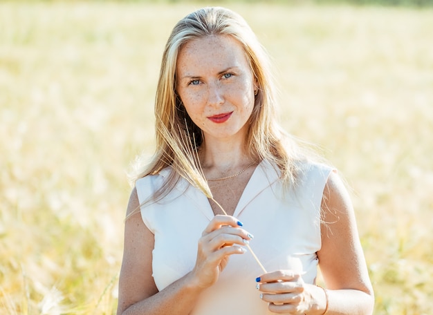 Beautiful blonde woman on a golden summer field