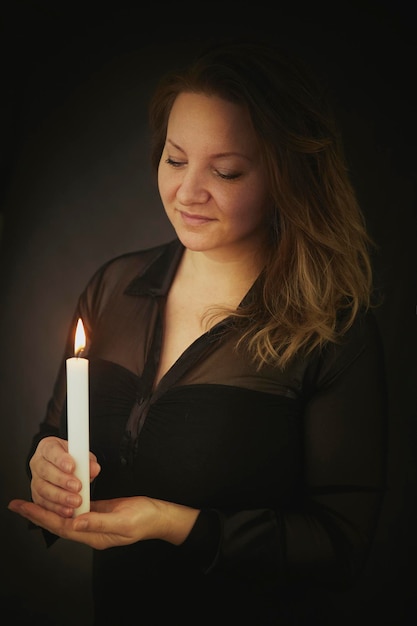 Beautiful blonde woman holding a candle in the dark