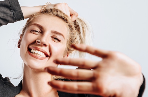 Photo a beautiful blonde woman makes hairstyle on a white isolated background