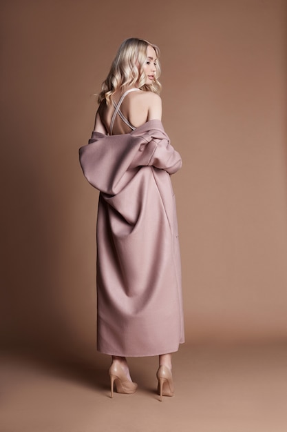 Beautiful blonde woman posing in a pink coat