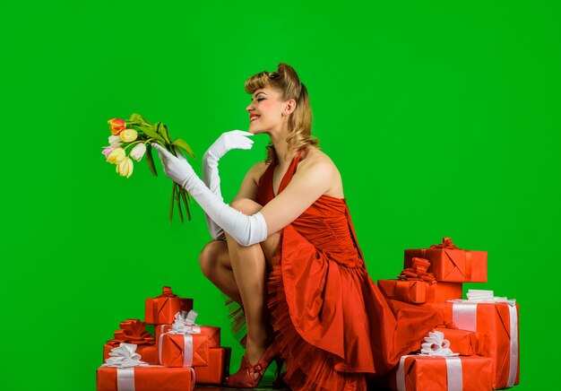 Красивая блондинка в красном платье с ретро прической счастливая девушка с подарочным букетом тюльпанов