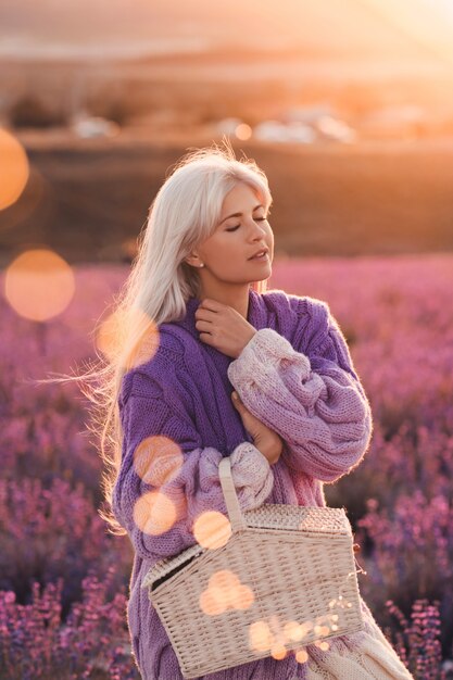 Photo beautiful blonde woman resting in lavender field holding straw basket