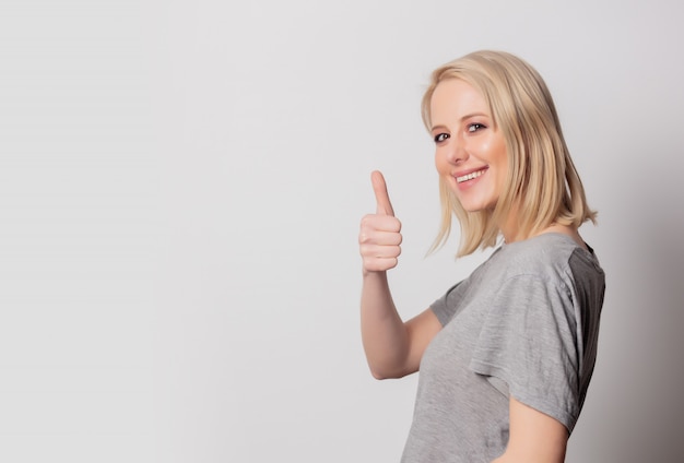 Beautiful blonde woman show OK gesture on white wall