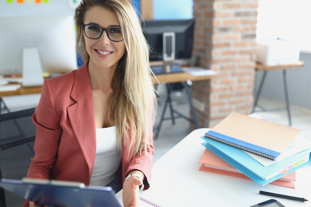 Beautiful blonde woman sit in cabinet with paperwork and laptop