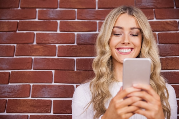 Beautiful blonde woman smiling and using smartphone